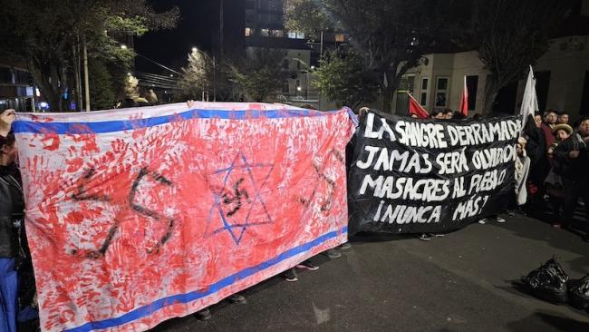 Manifestación en La Paz, Bolivia, con dos pancartas. Una muestra una bandera israelí cubierta de huellas de manos rojas y esvásticas. En la otra se lee: “La sangre derramada nunca será olvidada. Masacres del pueblo nunca más”. (Camila Azeñas)