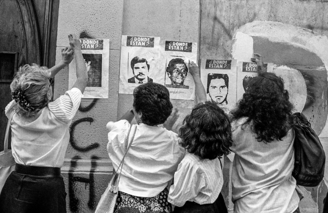 Relatives of the disappeared put up posters asking "¿Dónde están? Where are they?" outside the Londres 38 detention center in Santiago during the final months of the Pinochet dictatorship, January 1990. (Paulo Slachevsky / CC BY-SA 4.0 DEED)
