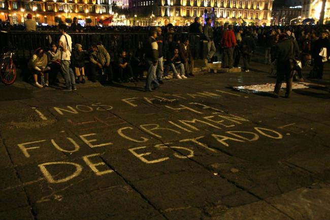 People gather in Mexico City on May 11, 2014, for a march commemorating the 43 who disappeared at Ayotzinapa. On the ground the slogan "Nos faltan los 43, fue crimen de estado" (We are missing the 43, it was a state crime) is written in chalk. (boerries neche/Flickr/CC BY-NC 2.0)