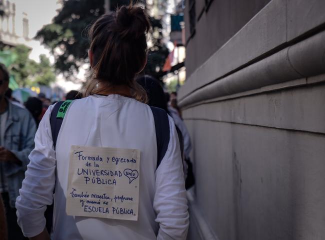 Una manifestante con un mensaje pegado a la espalda, declarando que fue formada en la universidad pública, ahora es maestra y también madre con hije en el sistema educativo público. Buenos Aires. 23 de abril de 2024. (Lizbeth Hernández)