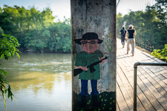 The columns of the bridge over the Caguán River are adorned with child-made paintings depicting smiling guerrilla fighters, in San Vicente del Caguán, January 2024. (Alejandro Jaramillo) 