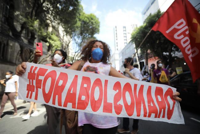 A demonstrator carries a banner protesting Bolsonaro in Salvador, Brazil, May 29, 2021. (Jonas Santos / Mídia NINJA / CC BY-NC 2.0)