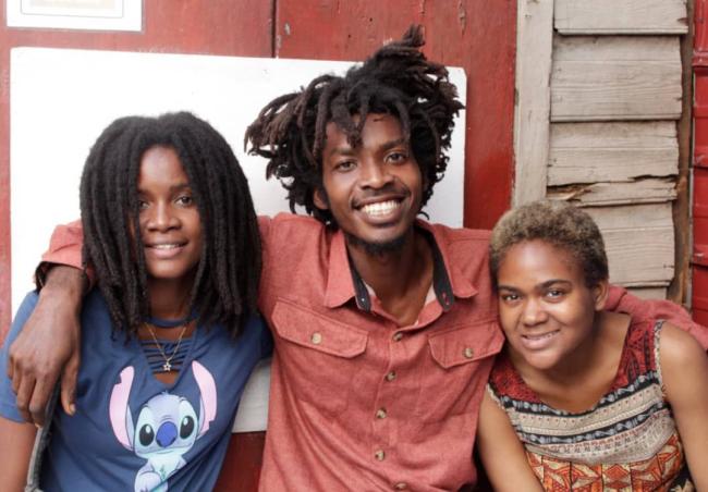 Tchadensky Jean Baptist (center), a student, artist, and anti-imperialist organizer was killed by a sniper in Port-au-Prince on March 21, 2023. He is pictured here with his partner Tedina and a community volunteer. (Image courtesy of the family)