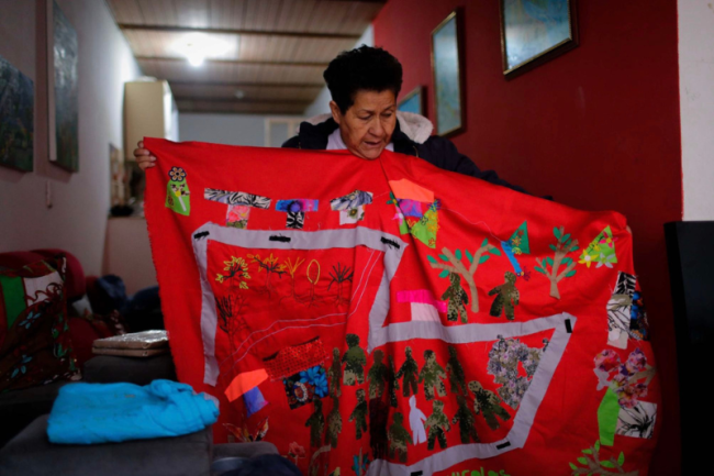 In her home, Blanca Monroy shows one of her sewing projects, in which the figure of her son appears surrounded by soldiers. (Andrés Torres Galeano)