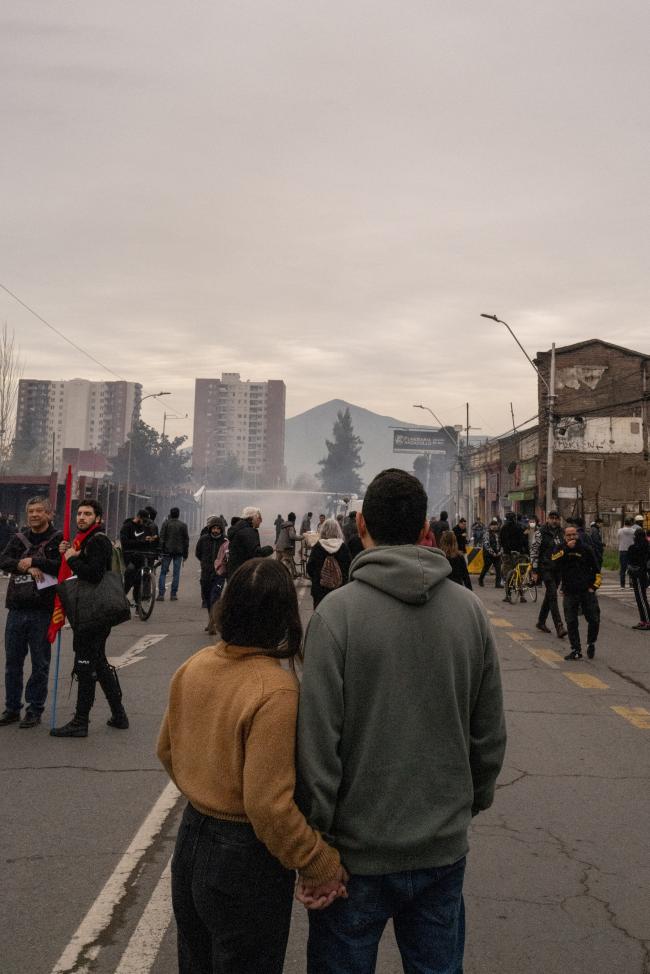 A young couple watch the Carabineros police force clash with protesters as they march towards the Cemeterio General to pay tribute to Salvador Allende. (Anita Pouchard Serra)