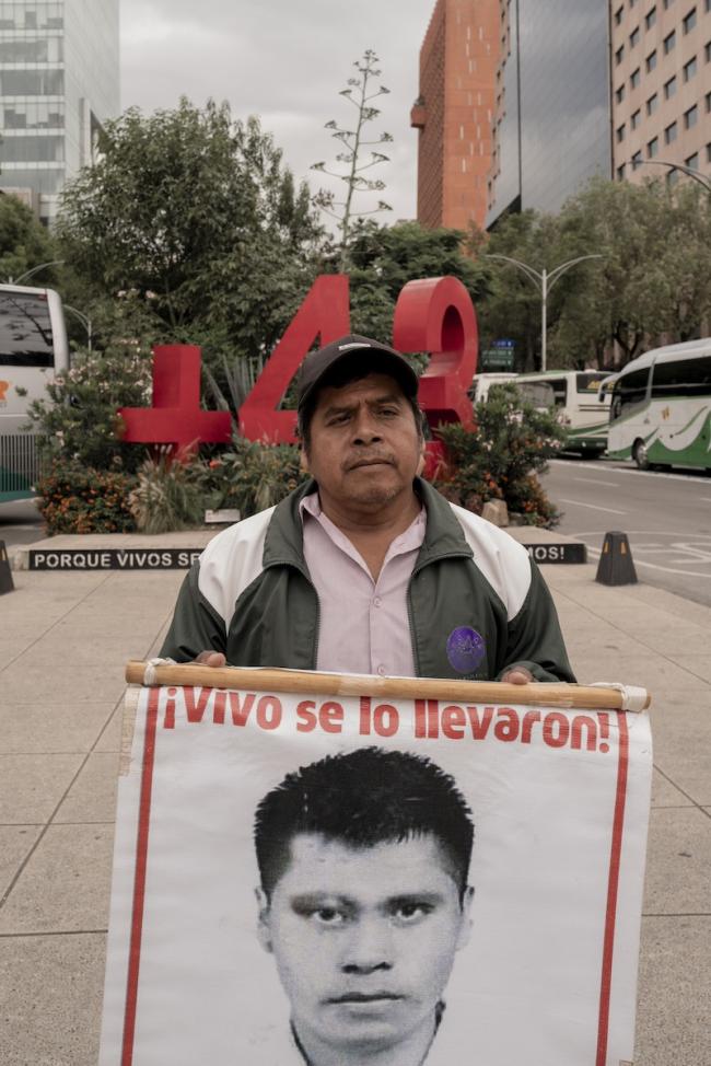 Francisco Lauro Villegas, a father of one of the missing Ayotzinapa students, attends the march holding a poster of his missing child. The poster features the phrase "Vivo se lo llevaron!" (¡Alive they took him!). (Anita Pouchard Serra)