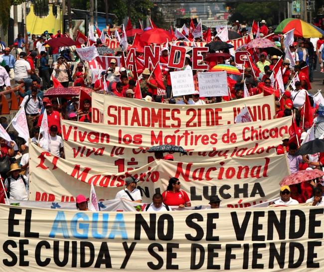 Demonstrators carry signs against water privatization at a May Day march in El Salvador. (Photo by CISPES)