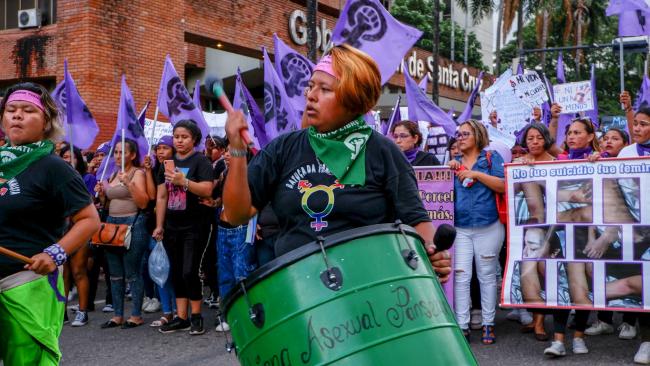 Feminist activists march together behind a drumline holding flags and signs in Santa Cruz de la Sierra, Bolivia. March 8, 2024. (Tanel Tilk)