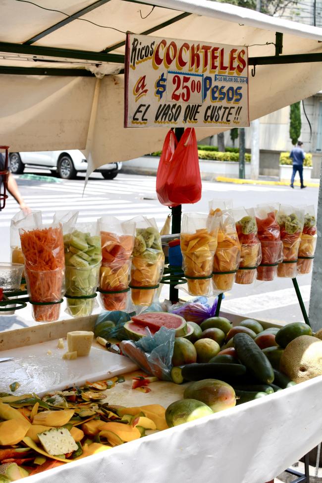 A fruit stand featuring a rótulo advertising cocktails (Madeline McSherry)