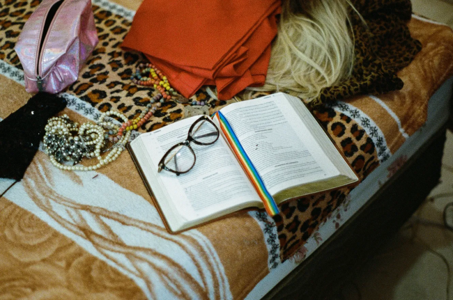A wig lies next to an open bible with a rainbow bookmark. (Felipe Avila)