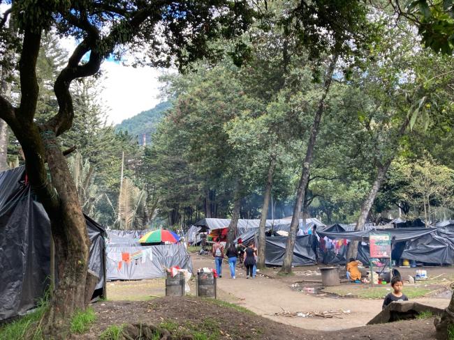 Camp members walk between tents in Bogotá's Olaya Herrera Park (Christoph Sponsel)