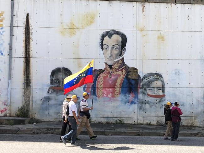 Supporters of Juan Guaidó walk past a mural of Simón Bolívar on their way to a rally in January 2019 in Caracas. (Photo by Rebecca Hanson)