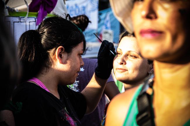 Una manifestante adorna el rostro de su amiga con brillo (Virginia Tognola)