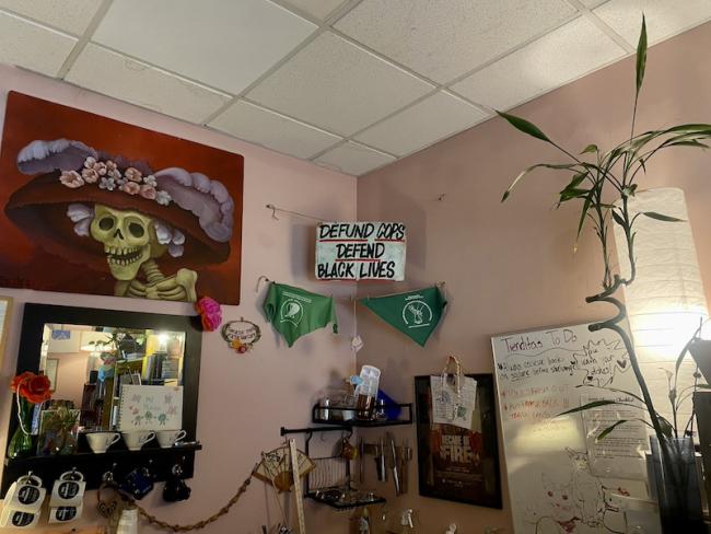 Inside the Mil Mundos bookstore, a sign hangs, reading “Defund Cops, Defend Black Lives” and another reads, “Smash the Patriarchy.” (Victoria Mortimer)