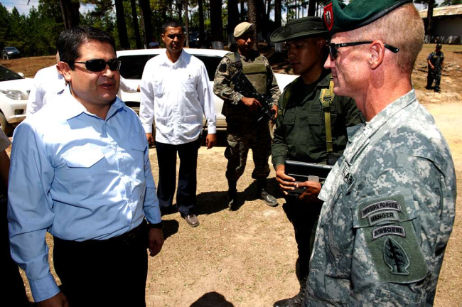 JOH (izquierda, con lentes de sol) conversa con un Boina Verde estadounidense en Tegucigalpa, Honduras. 7 de abril de 2014. (Servicio de Distribución de Información Visual de Defensa / Dominio público)