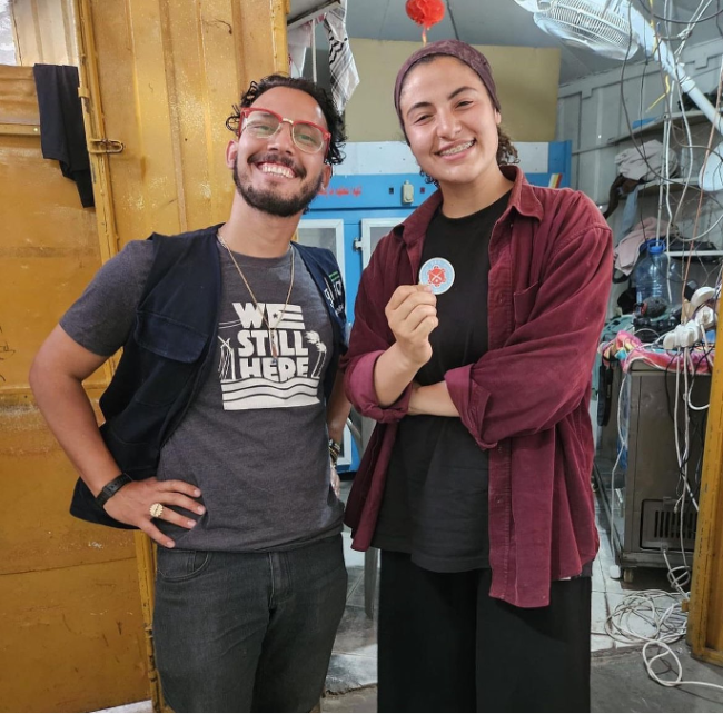 Libre Sankara and Bisan Owda, a Palestinian journalist, inside a medical center in Gaza. Owda is holding a button from the Puerto Rican diaspora group Diaspora Pa’Lante Collective. (Image courtesy of The Glia Project)