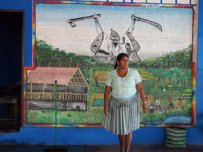 A Quechua woman stands in front of a mural celebrating coca grower resistance in the Chapare. (Thomas Grisaffi) 