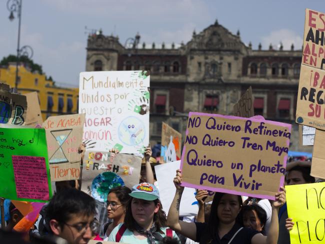 Demonstrators protest against the construction of Tren Maya in Mexico City in 2019. One sign in purple reads “I don’t want refinery. I don’t want Tren Maya. I want a planet to live on” (Francisco Colín Varela / Wikimedia Commons / CC BY 2.0)