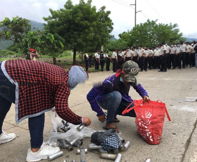 People gather spent tear gas canisters on the road. ((Baudilio Choc / Radio Victoria)