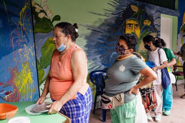 People queue at the Proyecto Florecer community kitchen in Medellín, which offers free lunches to neighbors, many of whom are Venezuelan migrants. (Yennifer Dallmann Villa)