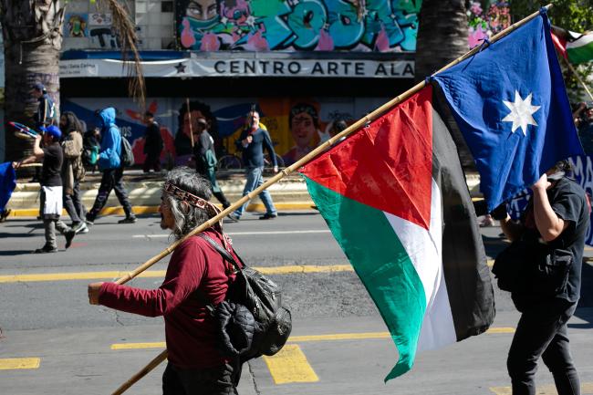 A demonstrator carries an ancient Mapuche and a Palestinian flag on October 9 at a march for Indigenous resistance in Santiago, Chile. (Folil Pueller)