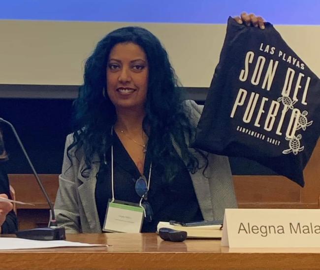 Abril 2023: Alegna Malavé Marrero con un bolso de mano "Las Playas Son del Pueblo," mientras formaba parte de un panel en la Universidad de Yale sobre Readaptando la Resiliencia. (Foto cortesía de Alegna Malavé Marrero)