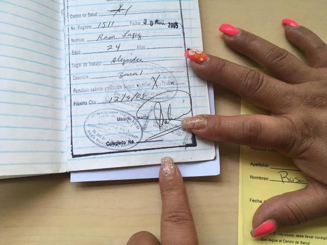 Samantha shows a page from the health booklet that was used to track the results of her regular police-enforced sexual health checks. She and her colleagues organized to get the practice outlawed in 2012 (Photo by Katie Schlechter).