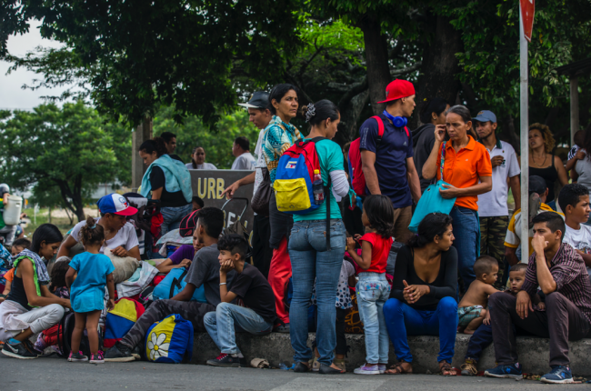 After leaving Venezuela, families sit on the sidewalk in front of a Red Cross help center in C cuta, Colombia, April 3, 2019. Some travel with a tricolored backpack. (UNHCR / Vincent Tremeau)