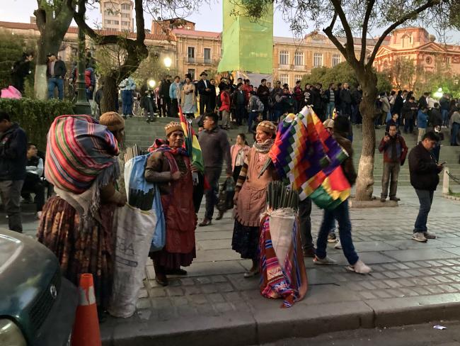 Women sell Bolivian national and wiphala flags to Arce supporters in Plaza Murillo. (Benjamin Swift)
