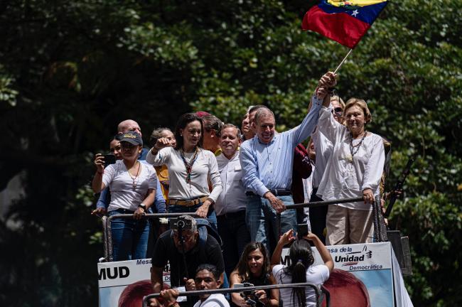 Presidential candidate Edmundo González Urrutia and opposition leader María Corina Machado wave to thousands of supporters from a truck during a rally after the elections in Altamira, eastern Caracas, on July 30, 2024. (Marcelo Pérez del Carpio)