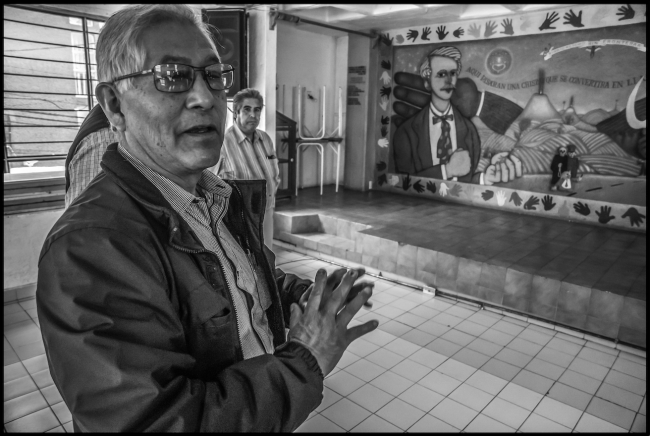 Benedicto Martínez, in the offices of the FAT in Mexico City, points to a mural by Mike Alewitz celebrating the binational solidarity partnership between the FAT and the United Electrical Workers. (David Bacon)