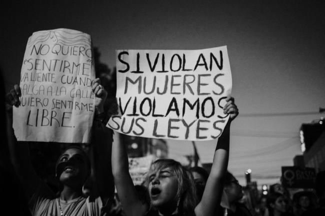 Una activista protesta con una pancarta: "Si violan mujeres, violamos sus leyes." (Foto por Laura Álvarez)
