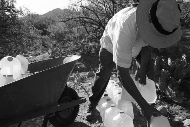 Mike Wilson, humanitarian aid worker and co-author of What Side Are You On? sets out water bottles for individuals traversing the desert in 2004. (Mitzue Aizeki)