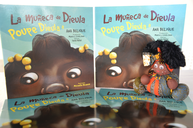 Una muñeca negra y el libro La muñeca de Dieula, Poupe Dieula, de Ana Belique. (Muñecas Negras RD)