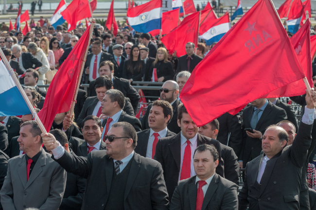 Asistentes a la toma de posesión del Presidente Mario Abdo Benítez ondean banderas del Partido Colorado y de Paraguay, el 15 de agosto de 2018. (Oficina Presidencial de Taiwán / Flickr / CC BY 2.0 DEED)
