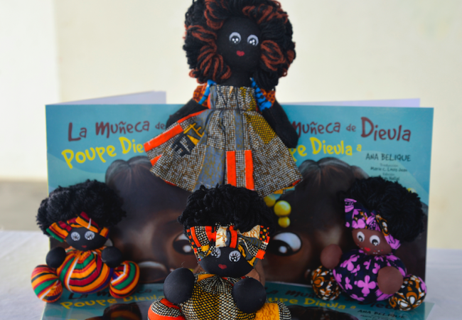 Unas muñecas negras y el libro La muñeca de Dieula, Poupe Dieula, de Ana Belique. (Muñecas Negras RD)