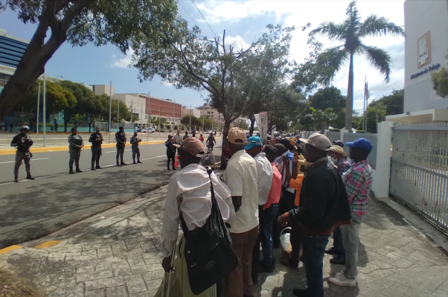 Retired cane workers face a line of police outside the Ministry of Labor in Santo Domingo, December 7, 2022. (Simón Rodríguez)